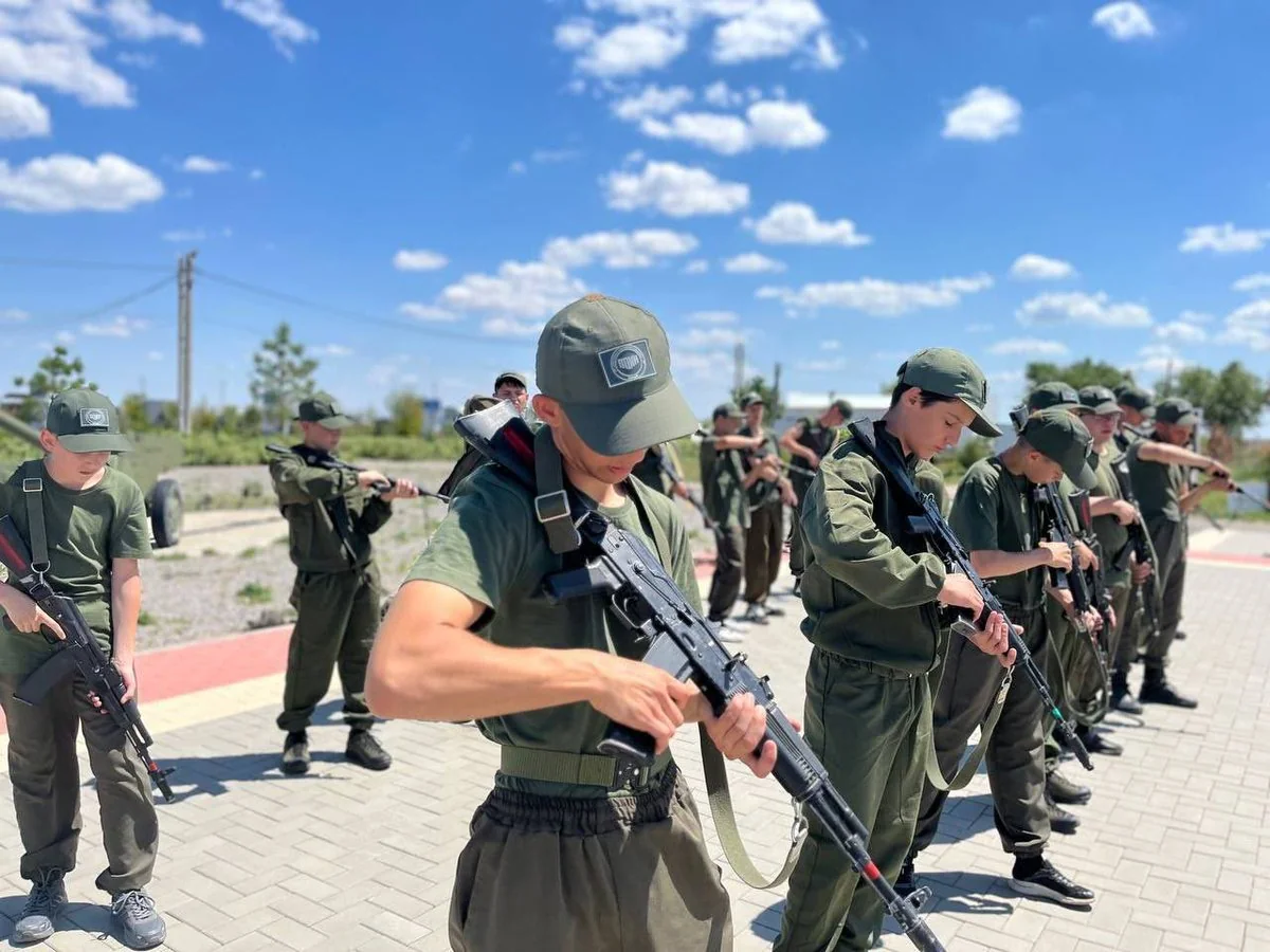 Молоді хлопці в зеленій формі з автоматами тренуються просто неба