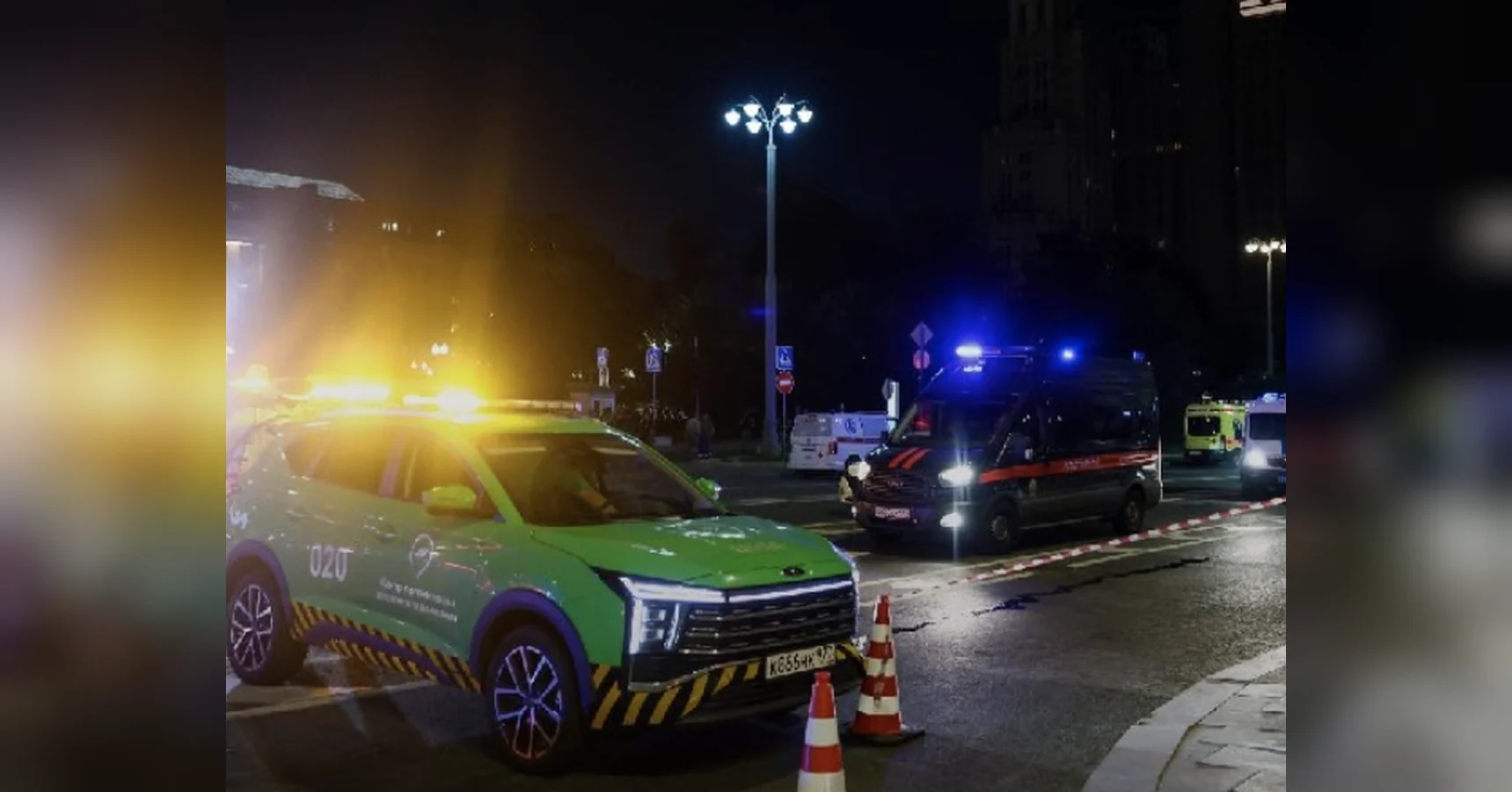 Нічна вулиця Москви з зеленим аварійним авто та поліцейським фургоном біля конусів